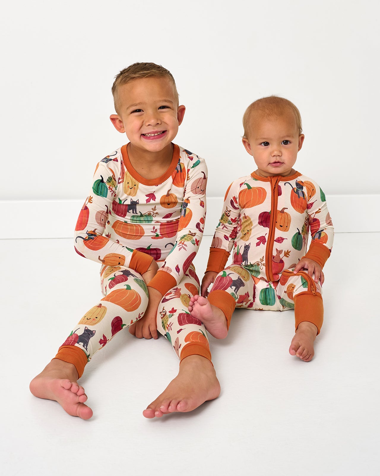 Two sitting children wearing matching Pumpkin Pals pajamas