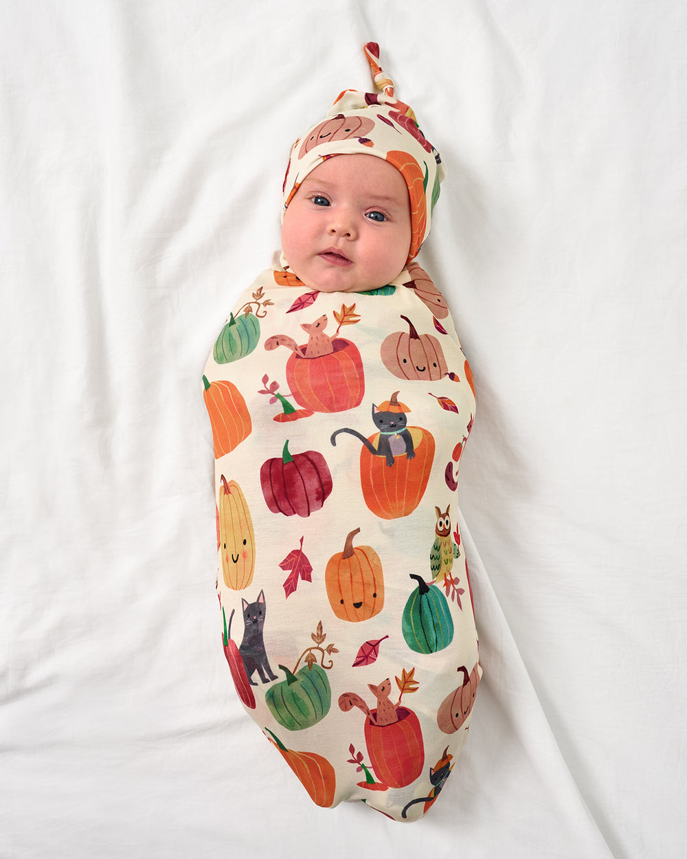 Baby wearing the Pumpkin Pals Swaddle & Hat Set