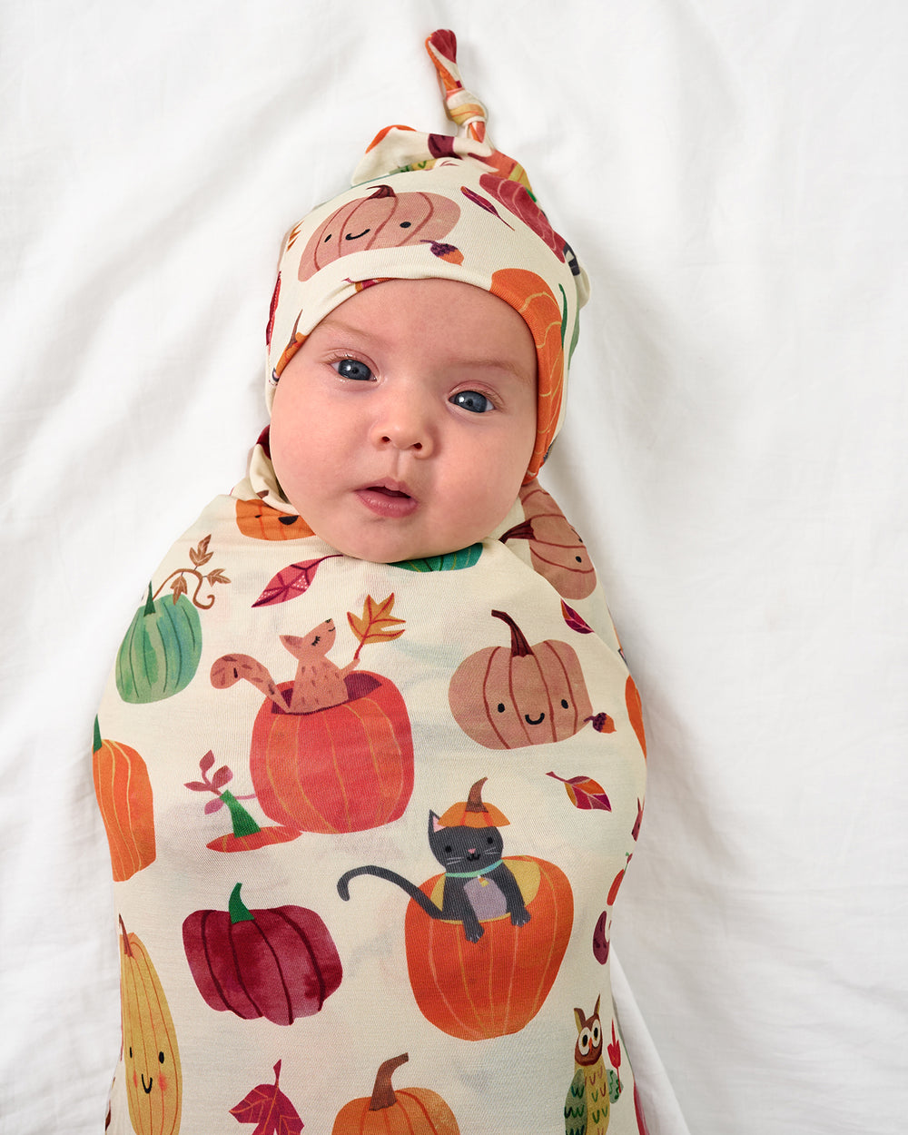 Close up of baby wearing the Pumpkin Pals Swaddle & Hat Set