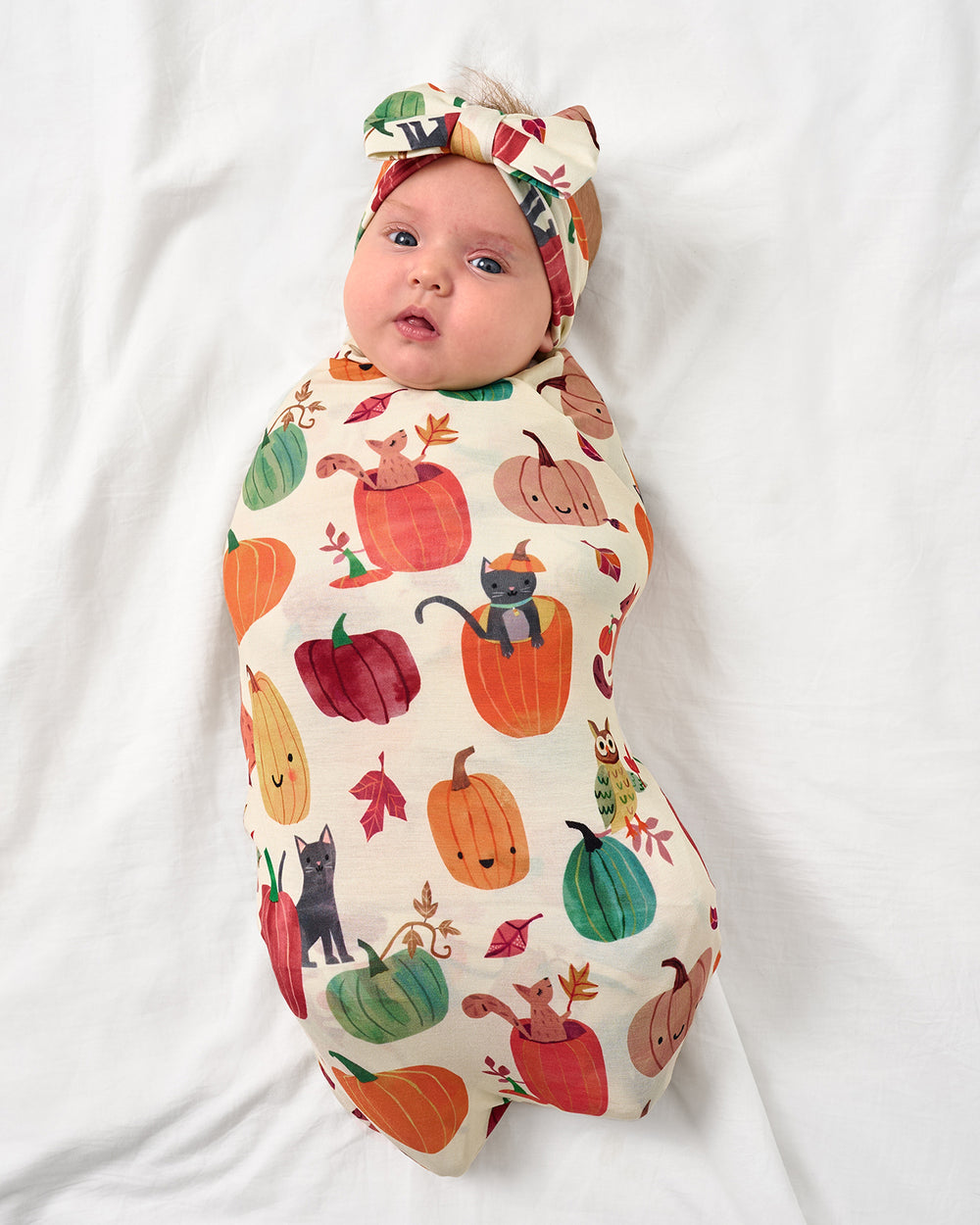 Aerial view of baby wearing the Pumpkin Pals Swaddle & Luxe Bow Headband Set
