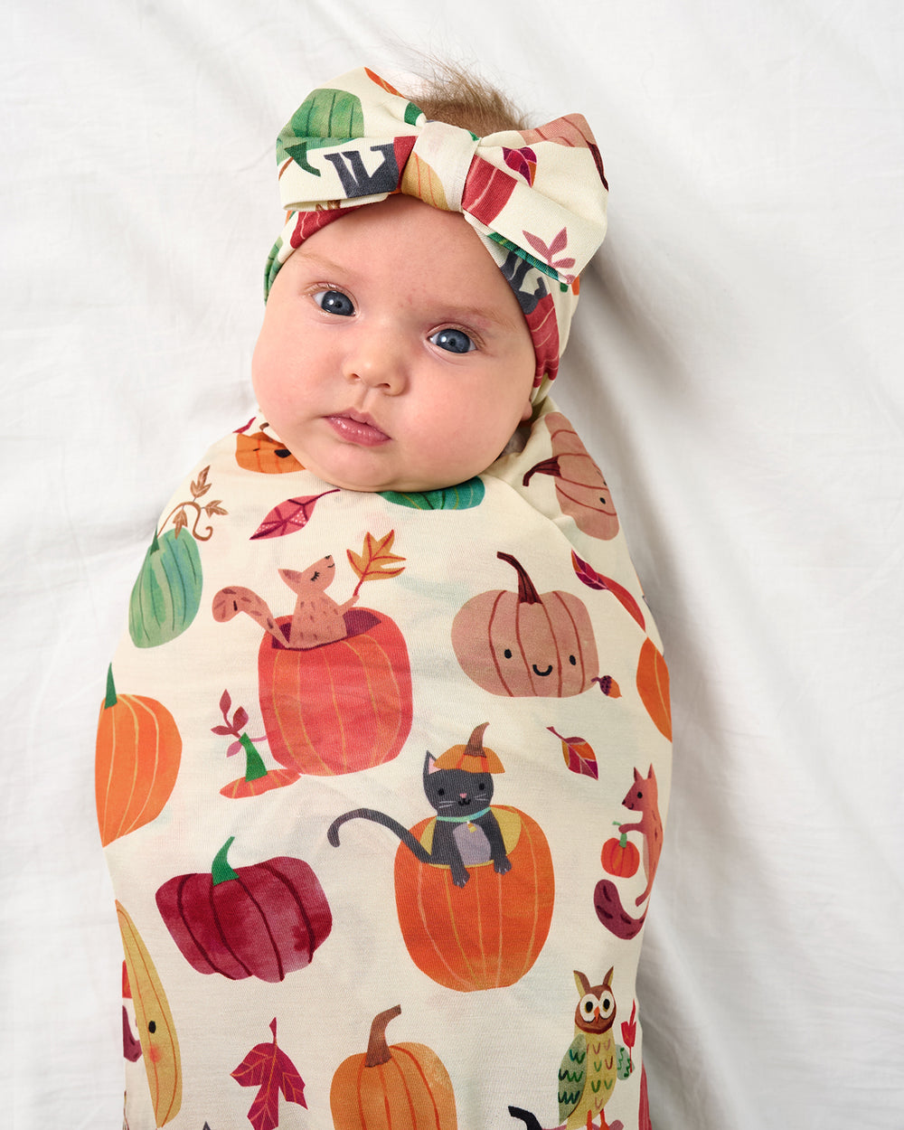 Close up of baby wearing the Pumpkin Pals Swaddle & Luxe Bow Headband Set