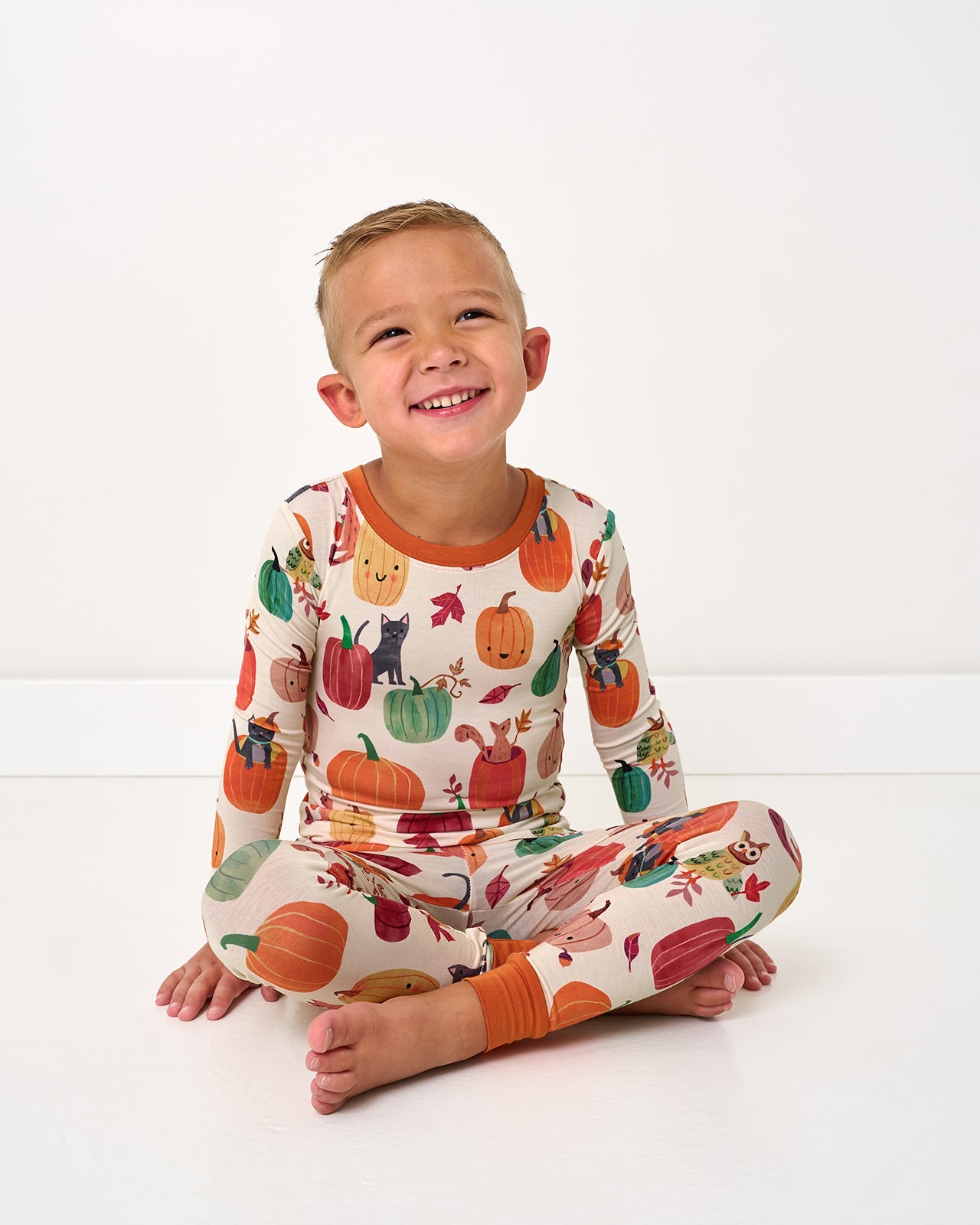 Sitting boy wearing the Pumpkin Pals Two-Piece Pajama Set