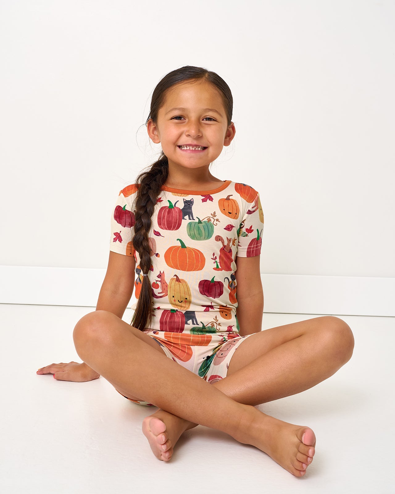 Sitting girl wearing the Pumpkin Pals Two-Piece Short Sleeve & Shorts Pajama Set