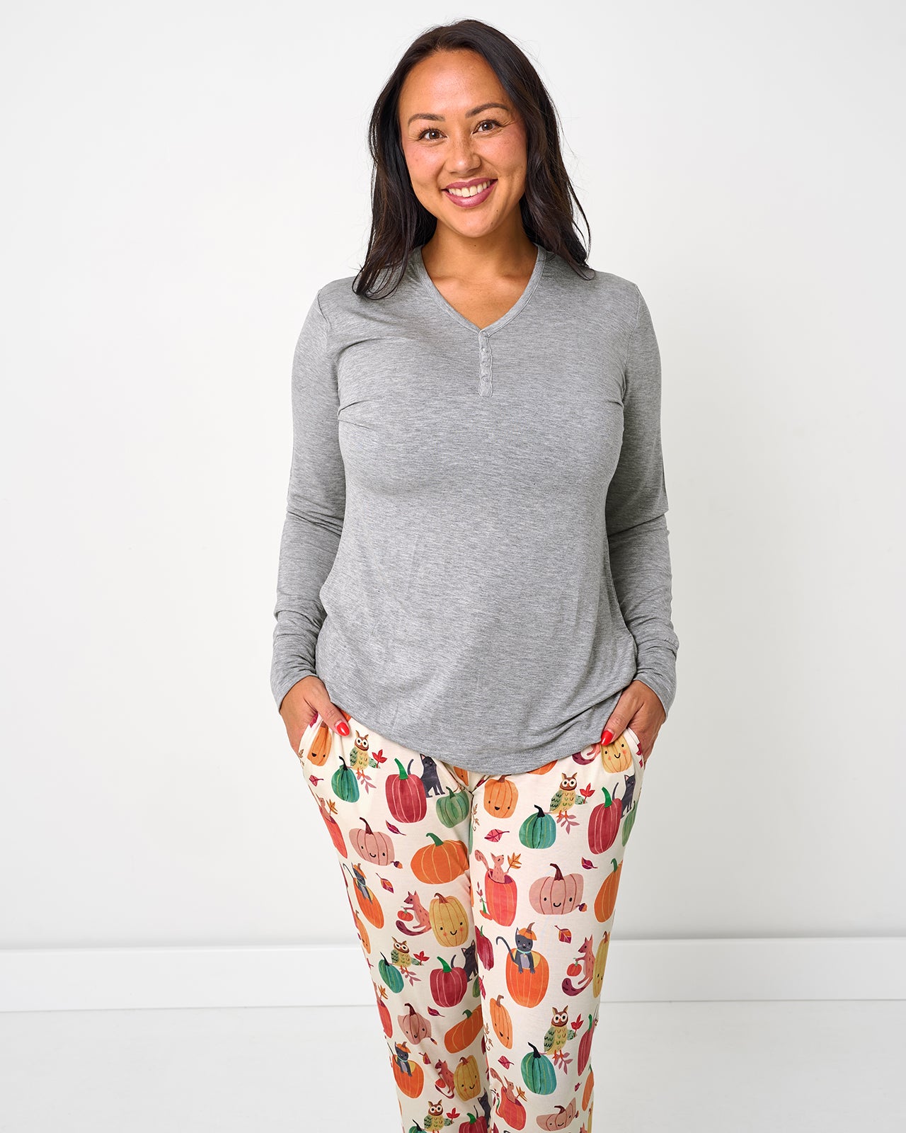 Standing woman wearing the Pumpkin Pals Women's Pajama Pants with a gray long sleeve pajama top