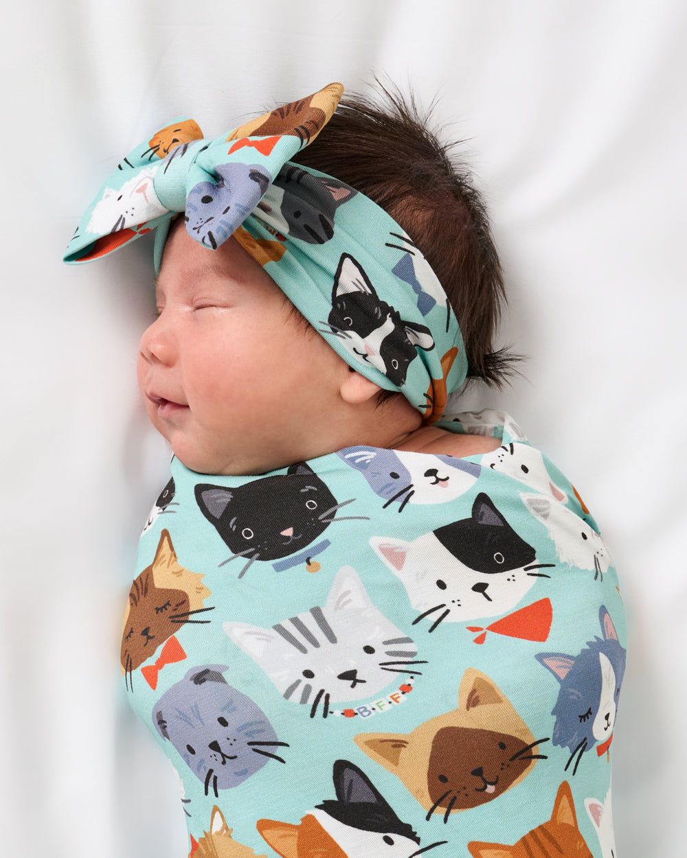 Close up of baby wearing the Purrfect Pals Swaddle & Luxe Bow Headband Set