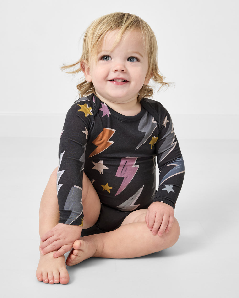 Sitting baby wearing the Rad Bolts Bodysuit on a white background
