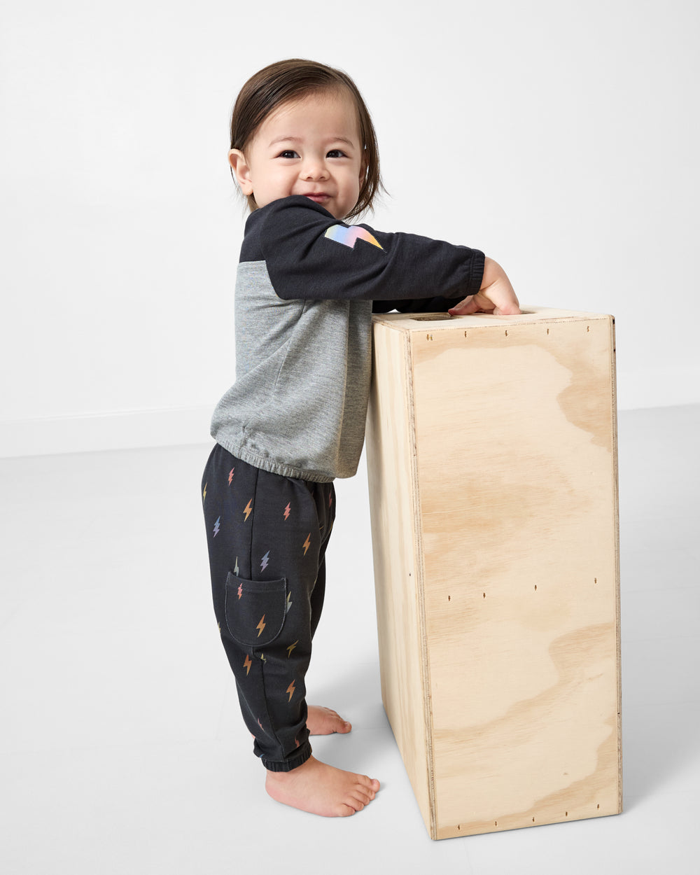 Standing toddler wearing the Rad Bolts Cinched Panel Crewneck and matching joggers