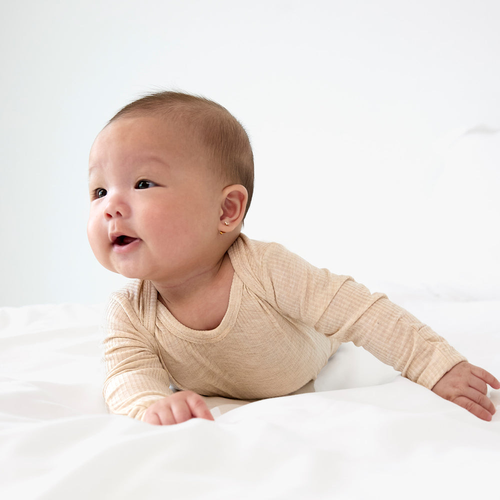 Child sitting up wearing oatmeal gown