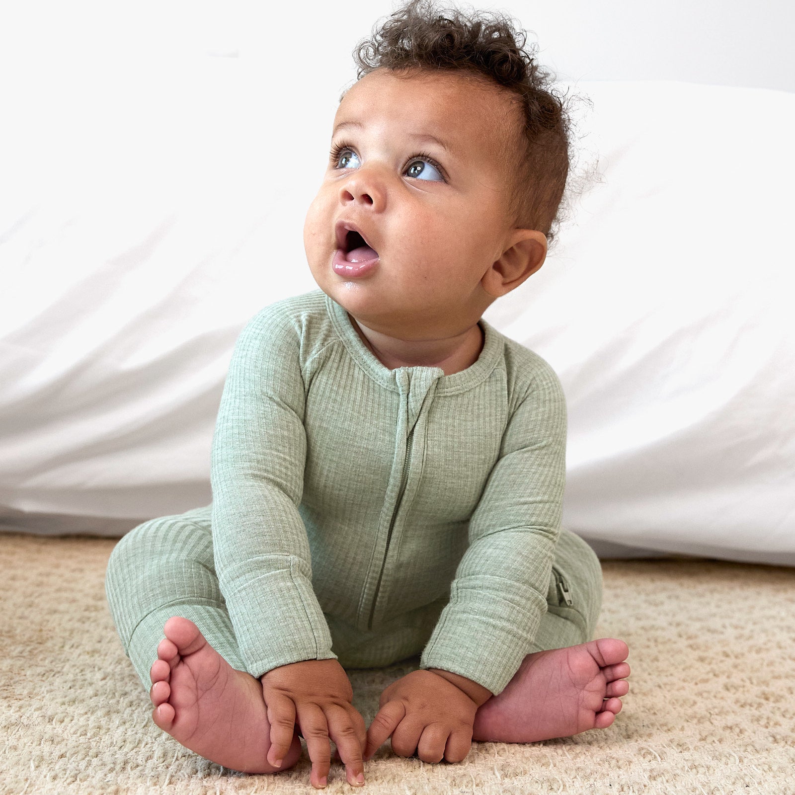 baby looking to the side wearing the heather sage zippy