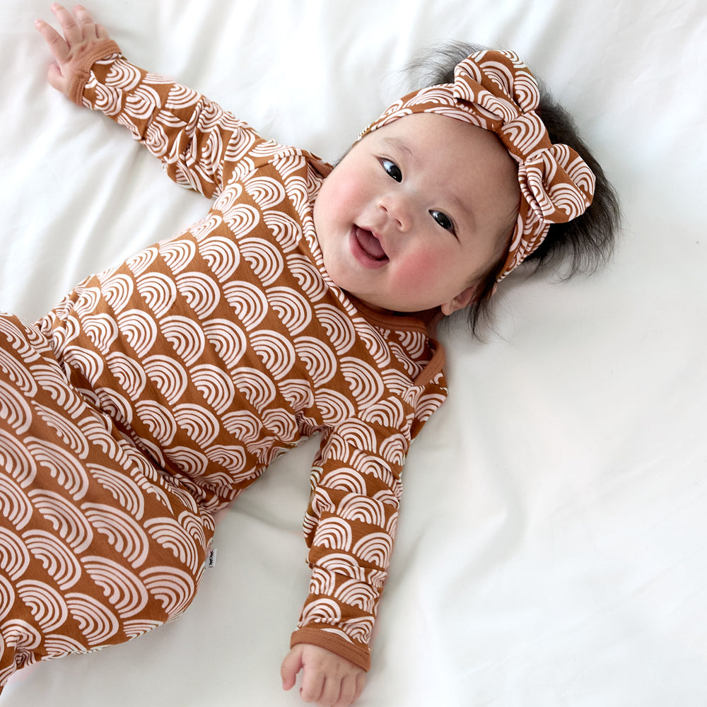 baby wearing rust rainbows gown close up 