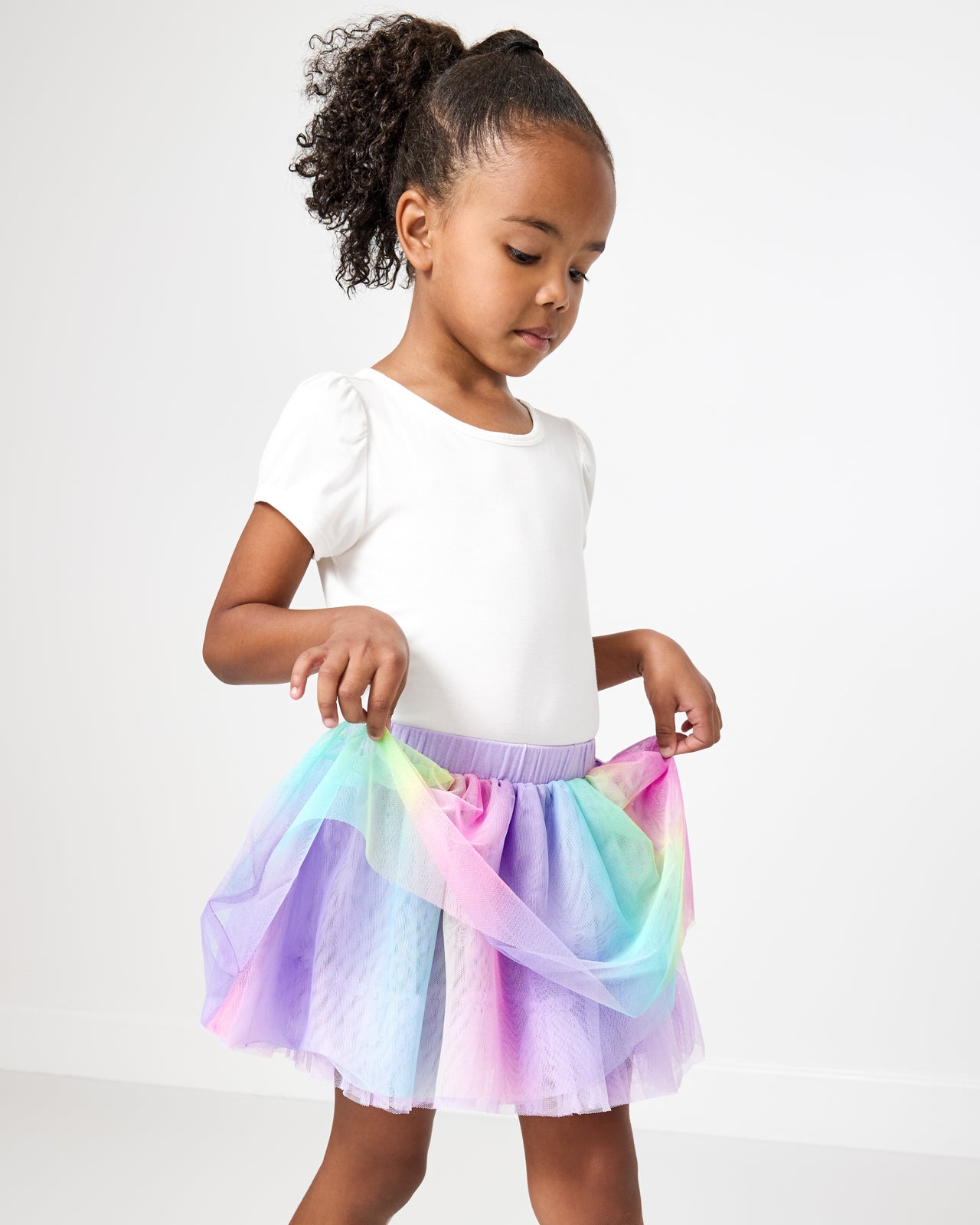 Girl holding up a tulle layer on the Rainbow Tutu Skirt