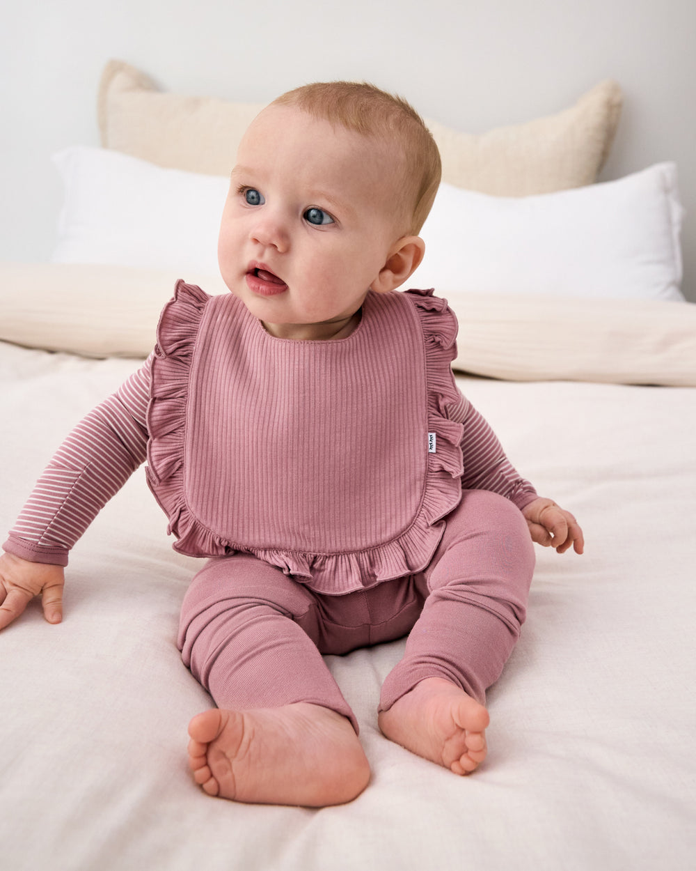 Sitting newborn wearing the Rosewood Ribbed Ruffle Bib