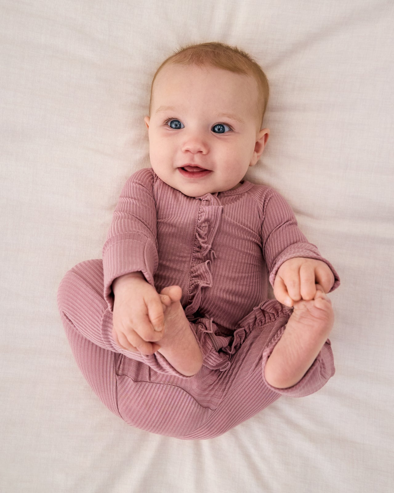 Aerial view of baby wearing the Rosewood Ribbed Ruffle Zippy