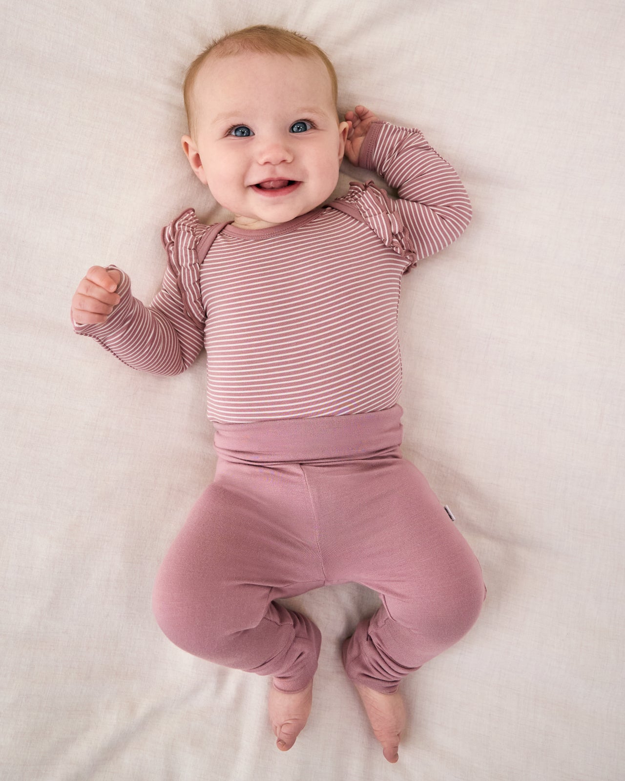 Aerial view of baby wearing the Rosewood Fold-Over Legging with a striped bodysuit