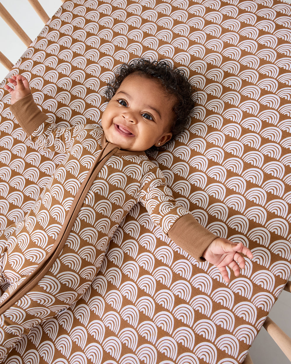 Alternate of baby laying on the Rust Rainbows Fitted Crib Sheet