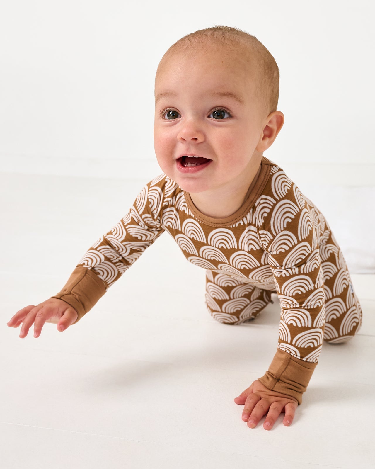 Crawling baby wearing the Rust Rainbows Crescent Zippy