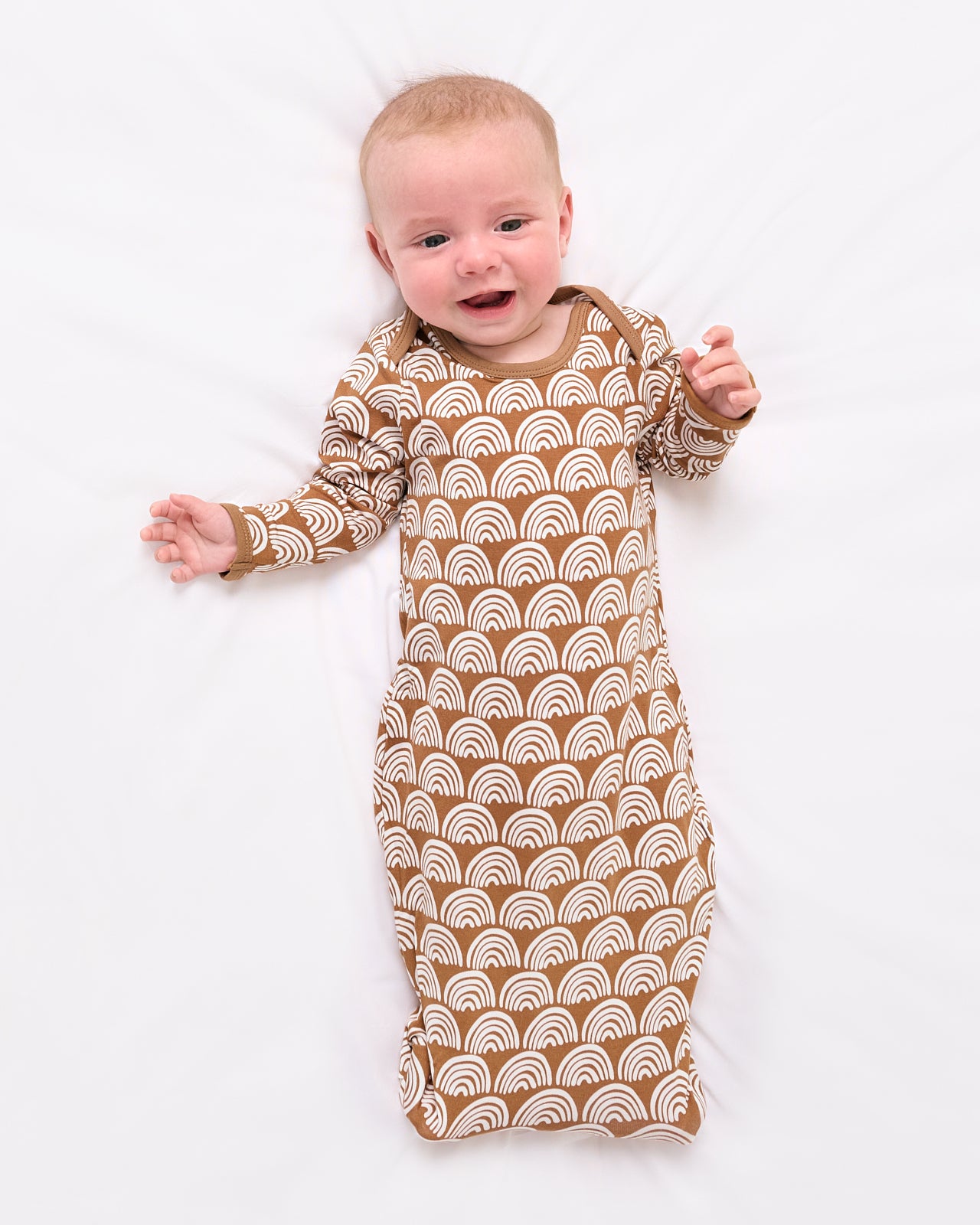 Aerial view of baby wearing the Rust Rainbows Infant Gown
