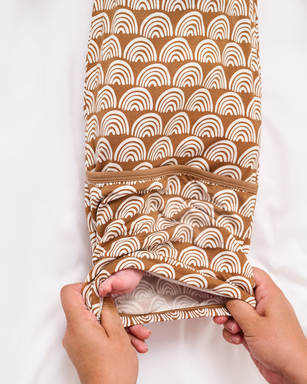 Adult demonstrating the envelope sweep on the Rust Rainbows Infant Gown