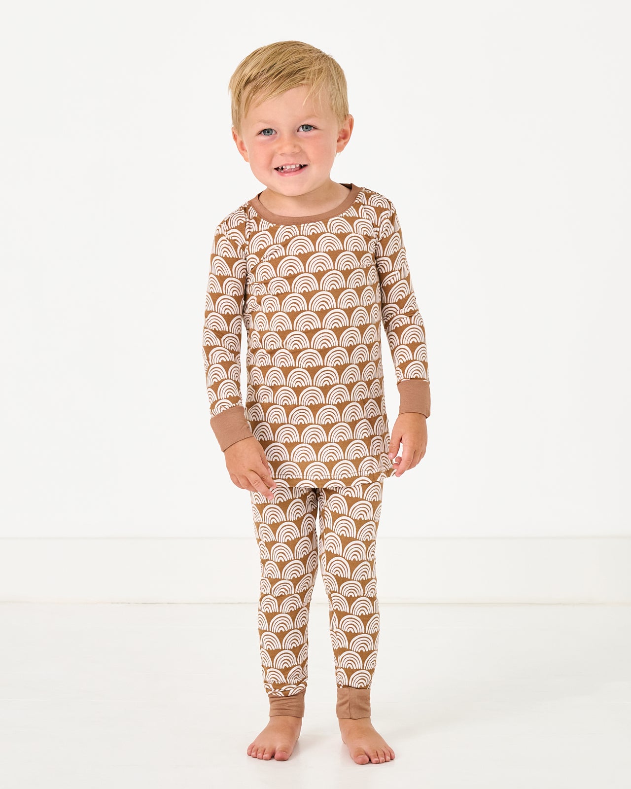 Standing boy wearing the Rust Rainbows Two-Piece Pajama Set