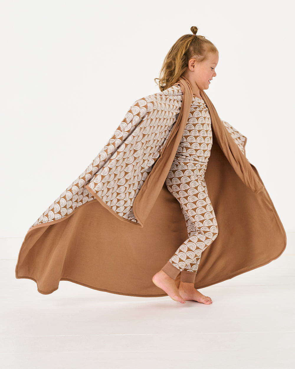 Child wrapped in the Rust Rainbows Large Cloud Blanket®