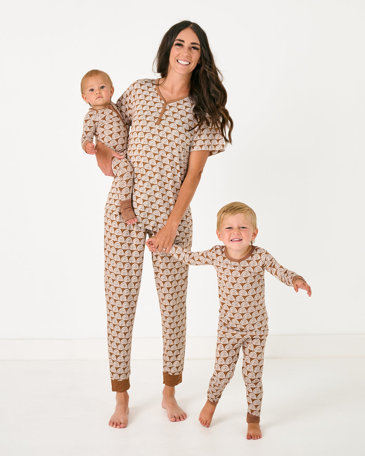 Family of three wearing matching Rust Rainbows pajamas