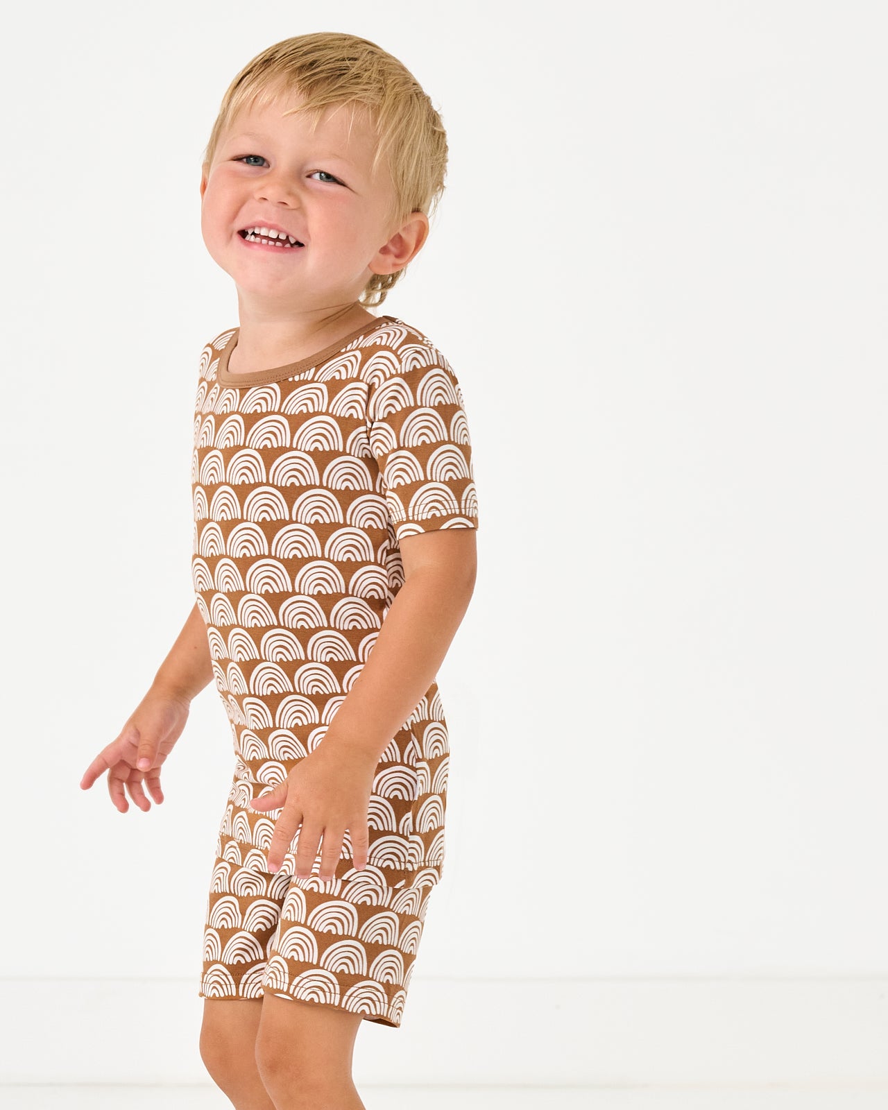 Boy wearing the Rust Rainbows Two-Piece Short Sleeve & Shorts Pajama Set