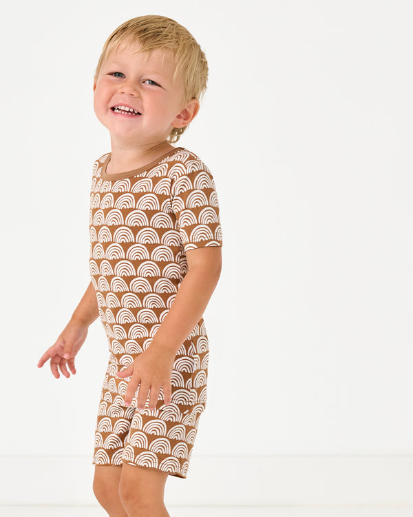 Boy wearing the Rust Rainbows Two-Piece Short Sleeve & Shorts Pajama Set