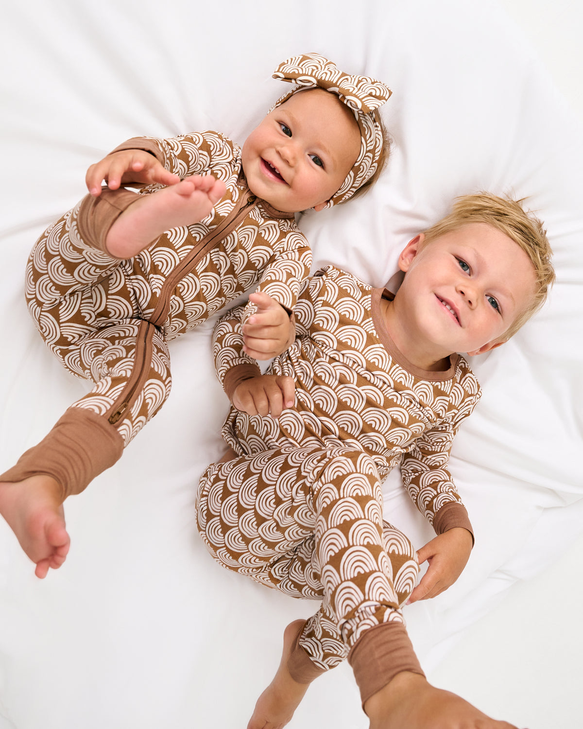Two children wearing matching Rust Rainbows gender neutral kids pajamas