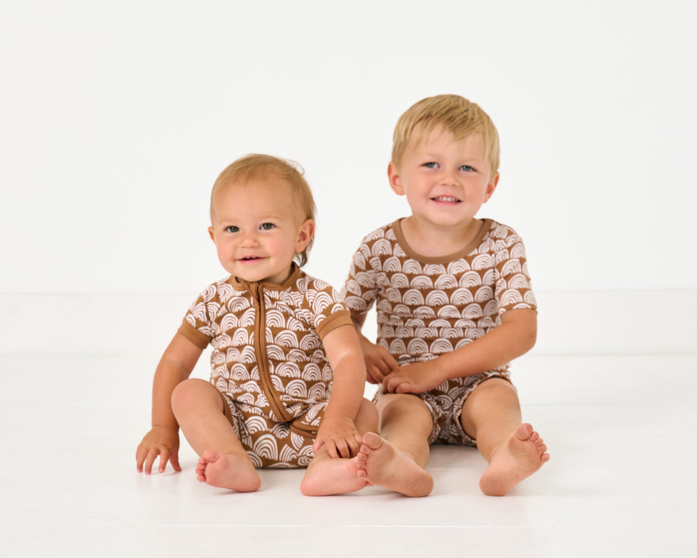Two siblings wearing matching Rust Rainbows bamboo pajamas
