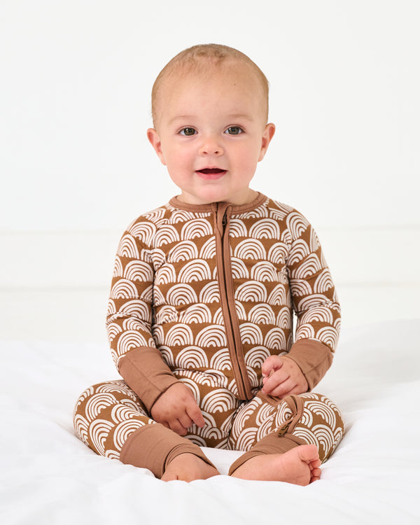 Sitting baby wearing the Rust Rainbows Zippy