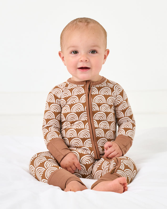 Sitting baby wearing the Rust Rainbows Zippy