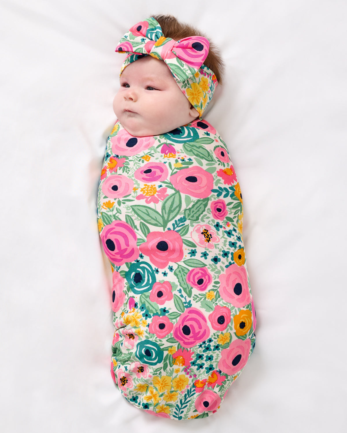 Aerial view of newborn wrapped in the Secret Garden Swaddle & Luxe Bow Headband Set