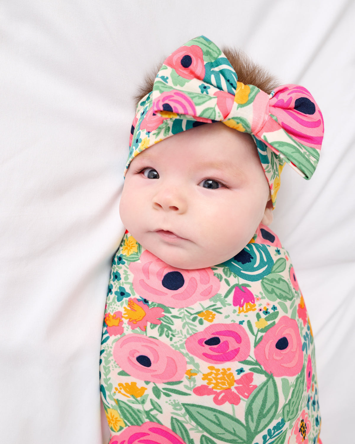 Close up of newborn in the Secret Garden Swaddle & Luxe Bow Headband Set