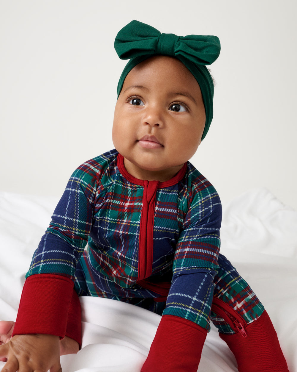 Newborn wearing the Emerald Luxe Bow Headband and Northern Night Plaid Zippy Baby Pajama