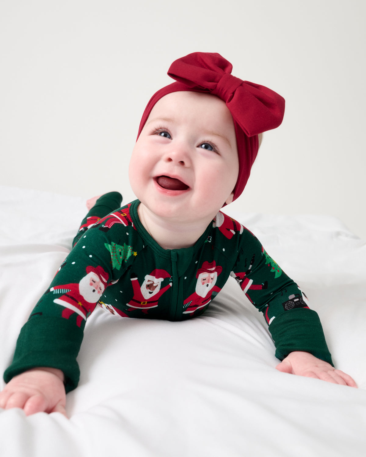 Newborn wearing the Santa's Grooves Zippy with a matching red luxe bow headband