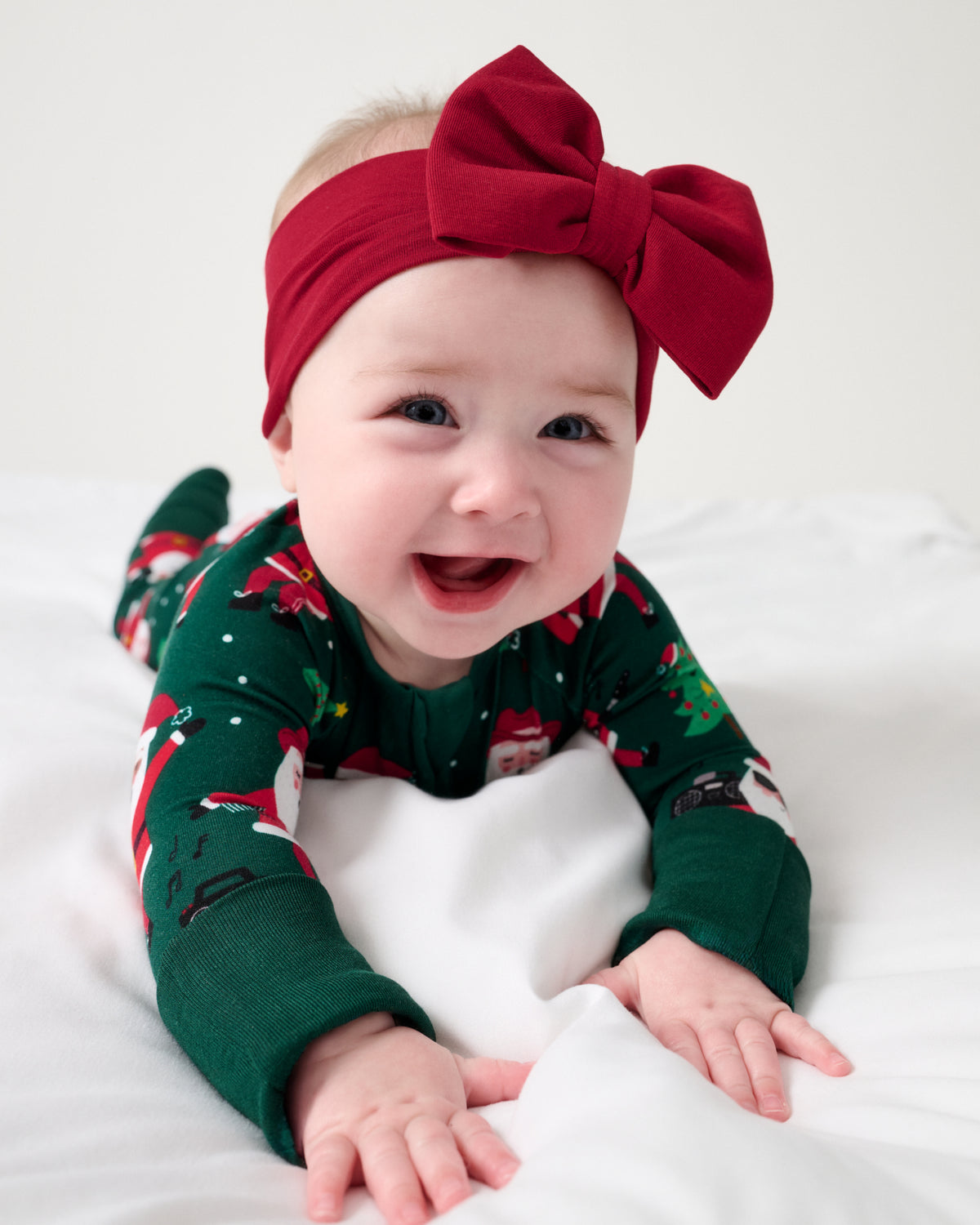 Baby wearing the Holiday Red Luxe Bow Headband with the Santa's Grooves Zippy