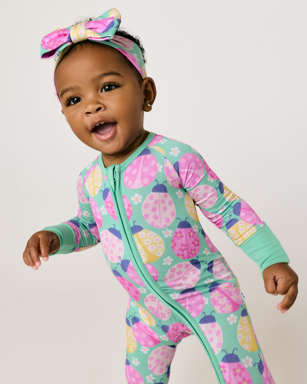 Baby wearing the Ladybug Meadow Luxe Bow Headband and Zipper Jammies