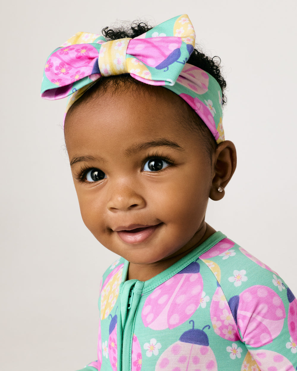 Close up of baby wearing the Ladybug Meadow Luxe Bow Headband
