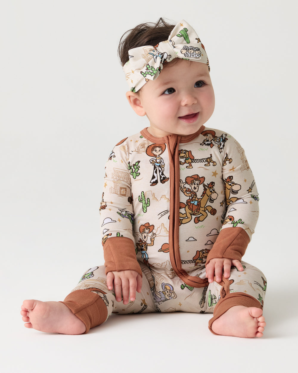 Sitting baby wearing the Disney & Pixar Woody's Wild West Luxe Bow Headband and Zippy