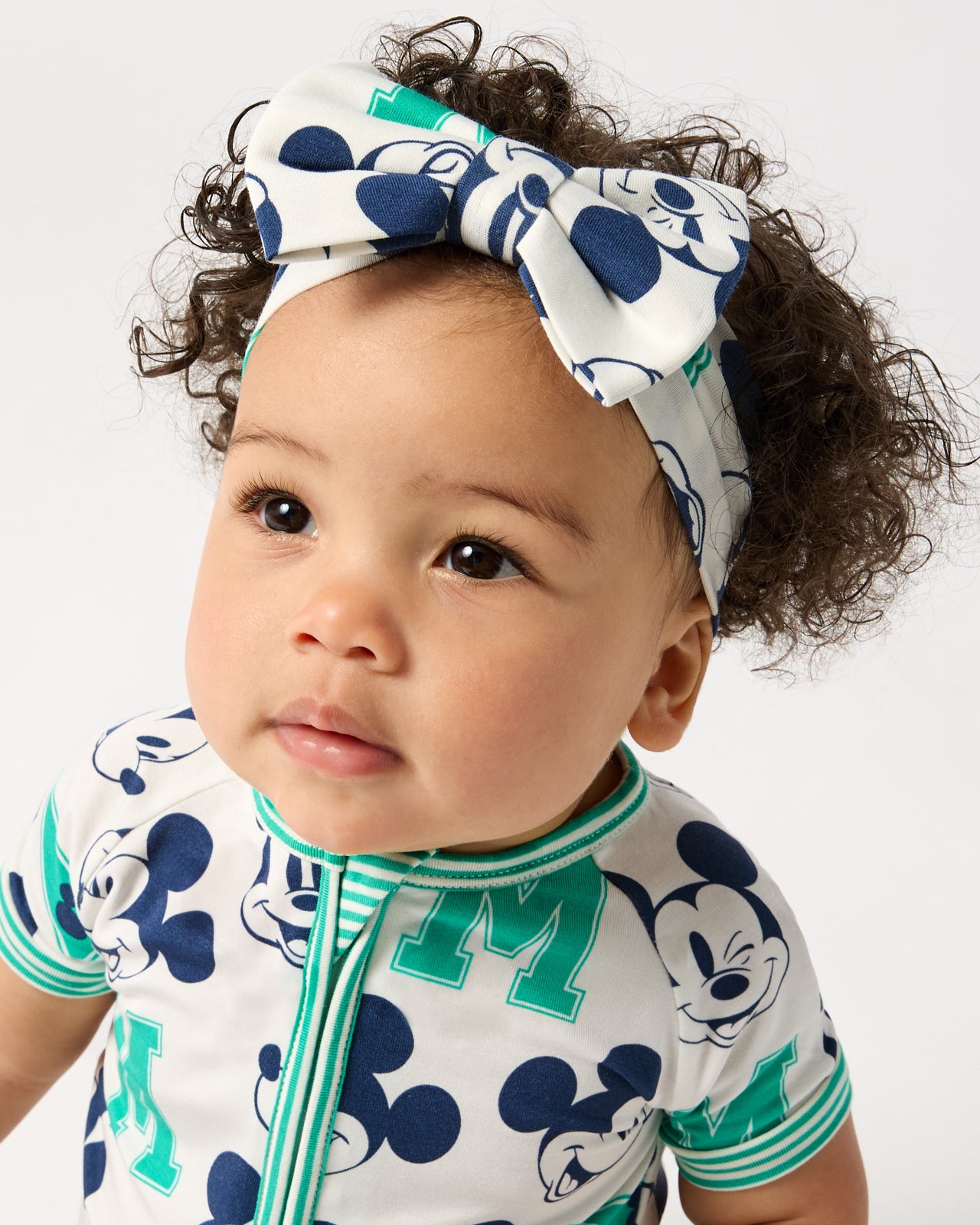 Close up of baby wearing the Disney Varsity Mickey Mouse Luxe Bow Headband