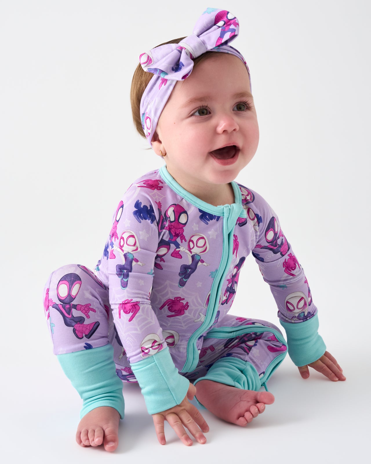 Sitting baby wearing the Spidey & Friends Tiny Webs Luxe Bow Headband and Zippy