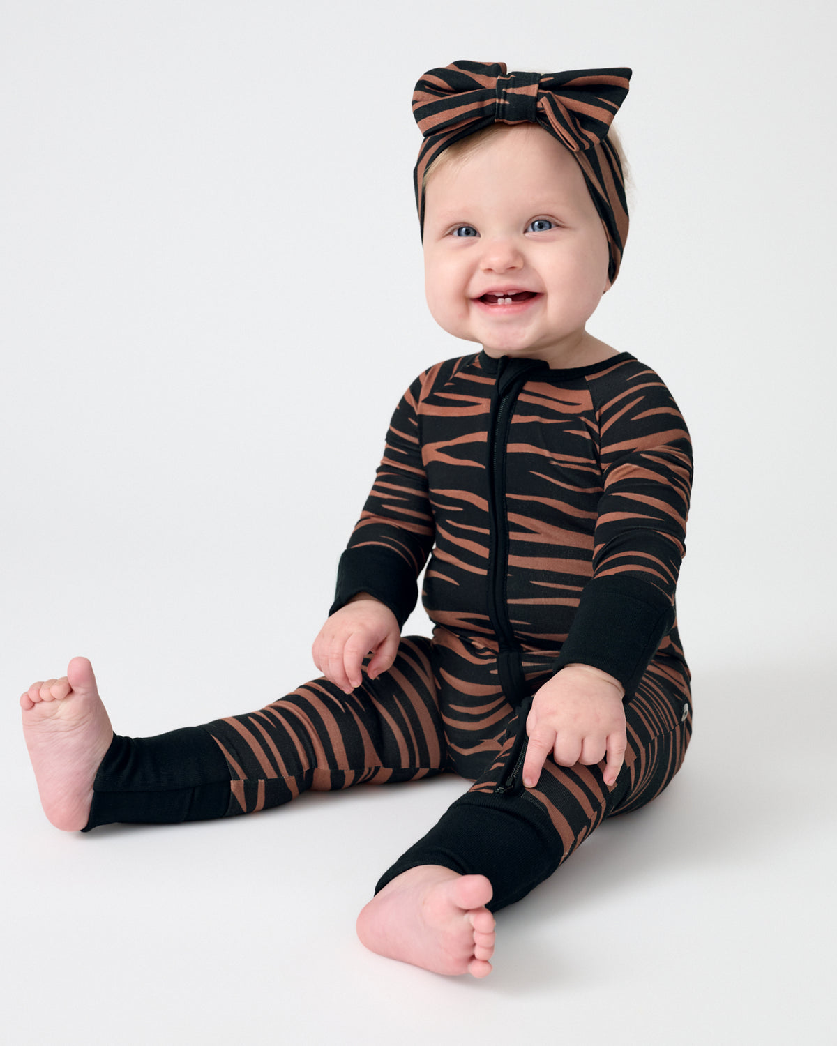 Sitting baby wearing the Wild Stripes Luxe Bow Headband and Zippy