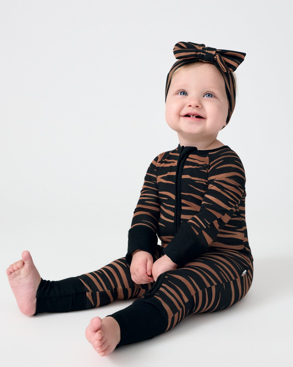 Sitting baby wearing the Wild Stripes Zippy and Luxe Bow Headband 