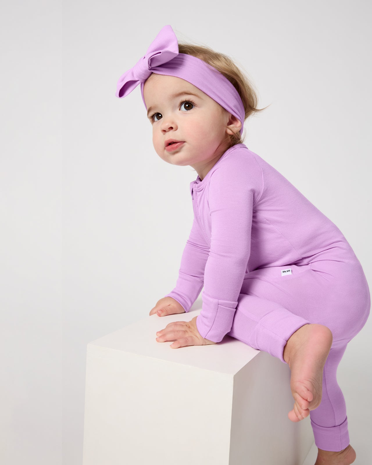 Baby crawling a wooden block wearing the Soft Wisteria Shorty Zippy