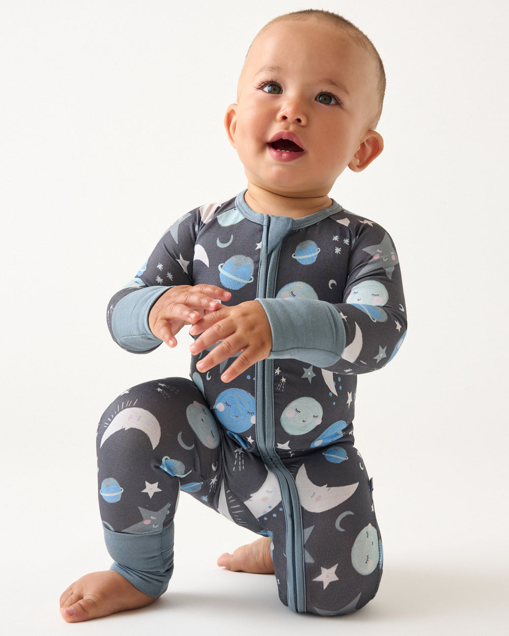 Kneeling baby boy wearing the Blue To the Moon & Back Zippy