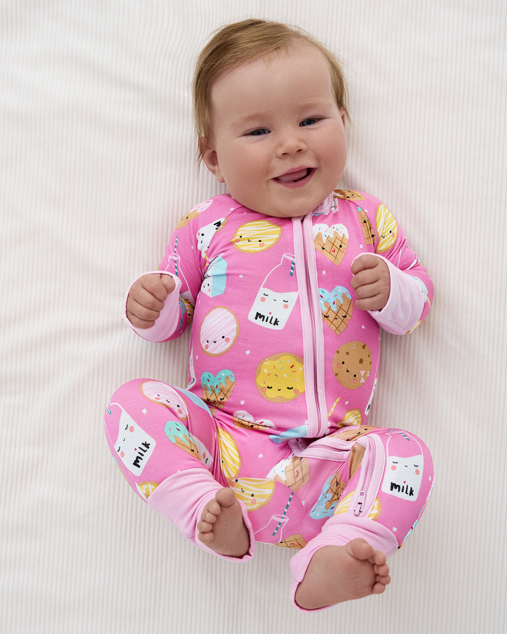 Aerial view of newborn wearing the Pink Cookies & Milk Zippy