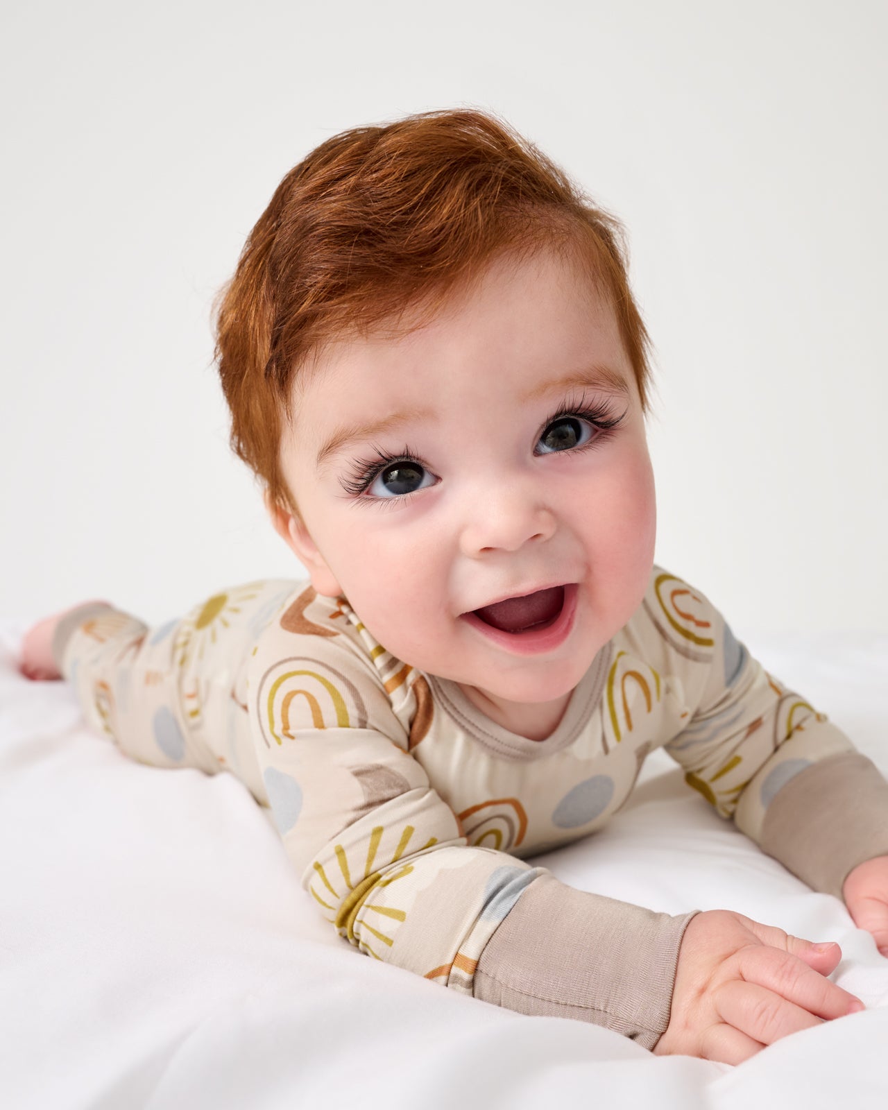 Baby on her tummy wearing the Desert Sunrise Crescent Zippy