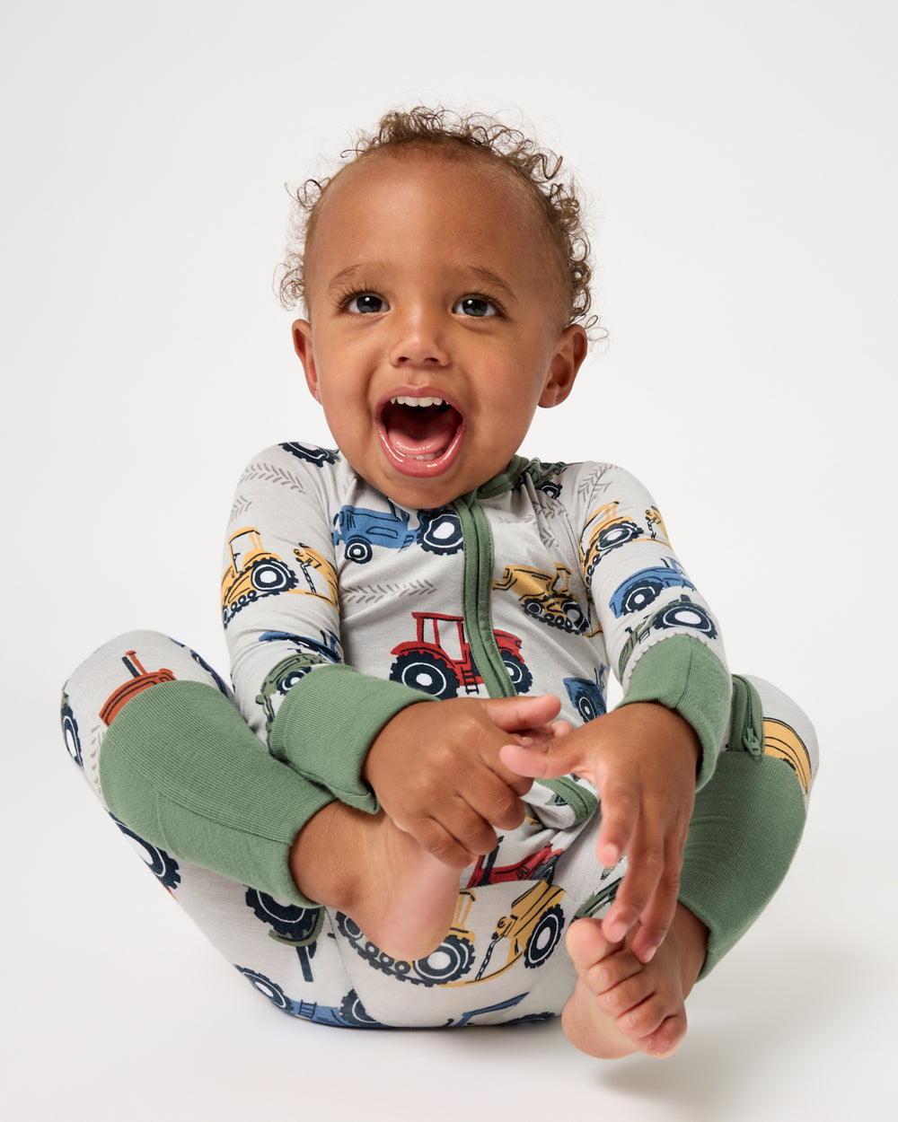 Smiling baby wearing the Tractor Tales Zippy