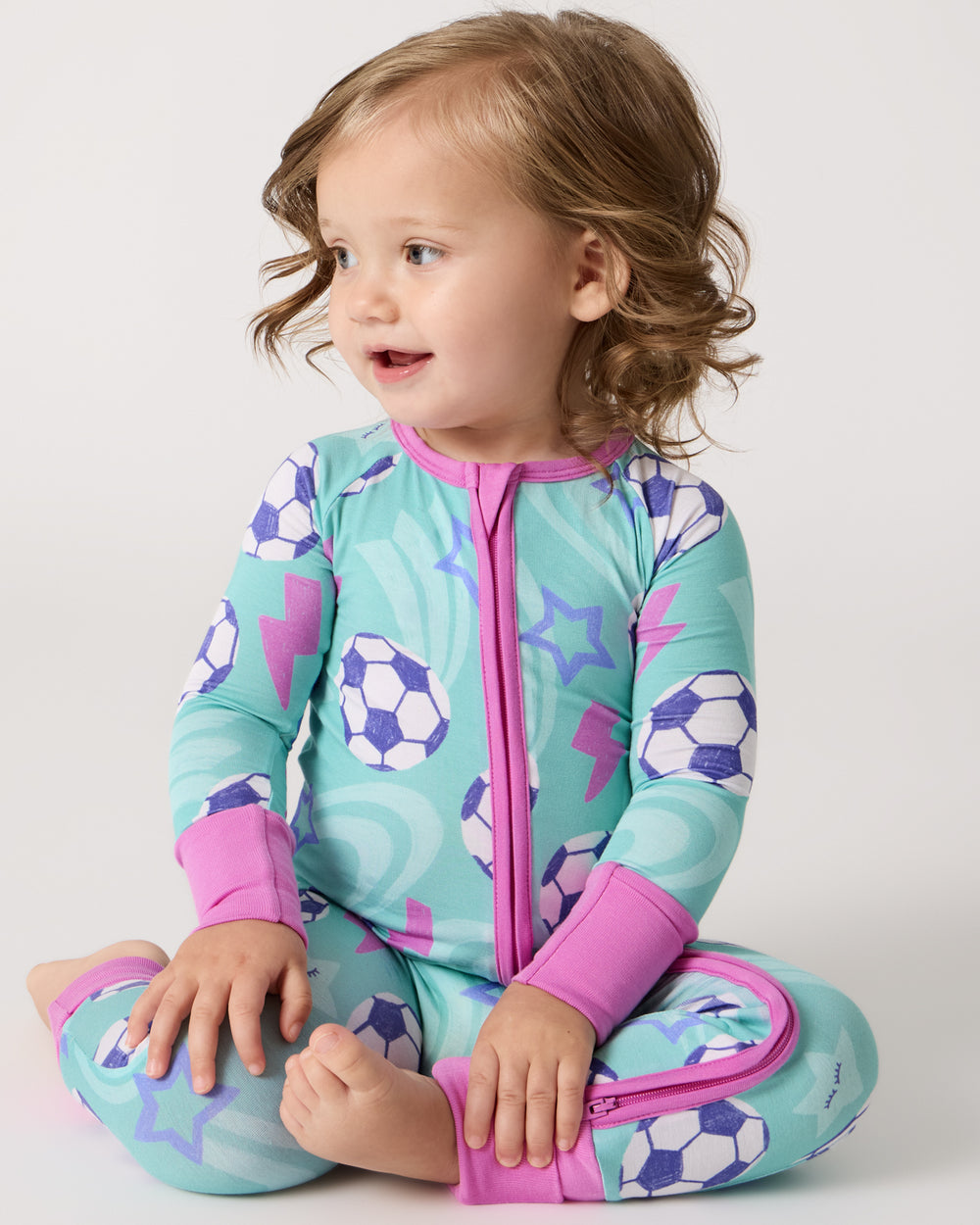 Sitting baby wearing the Aqua Soccer Stars Zippy