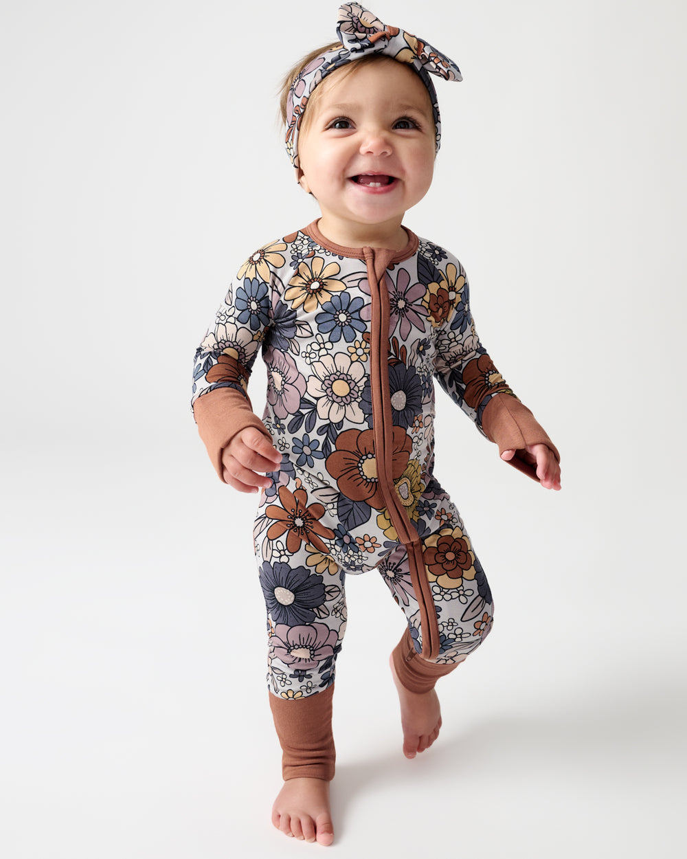 Walking baby wearing the Wildwood Floral Zippy and Luxe Bow